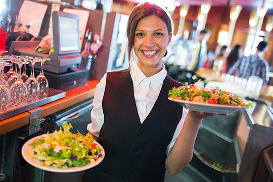 Bild Nebenjob als Kellner / Servicekraft – Kellnerin beim Servieren von Salaten in einem Restaurant.
